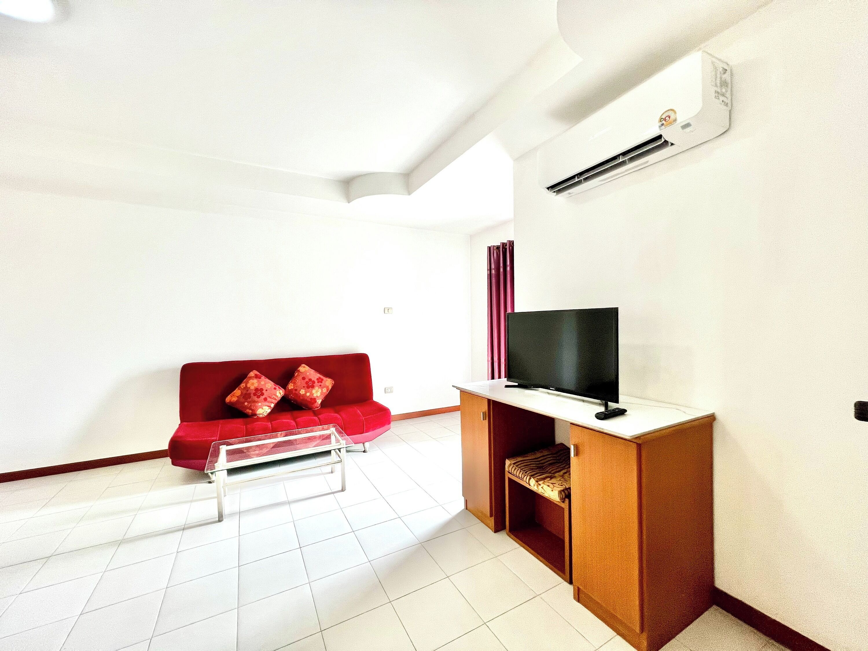 A compact living space with a red sofa, a flat-screen TV, and a wooden cabinet.