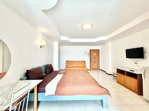 A hotel room with a bed, a TV, a desk, and a mirror. - BT Grand Condotel (Udon Thani)