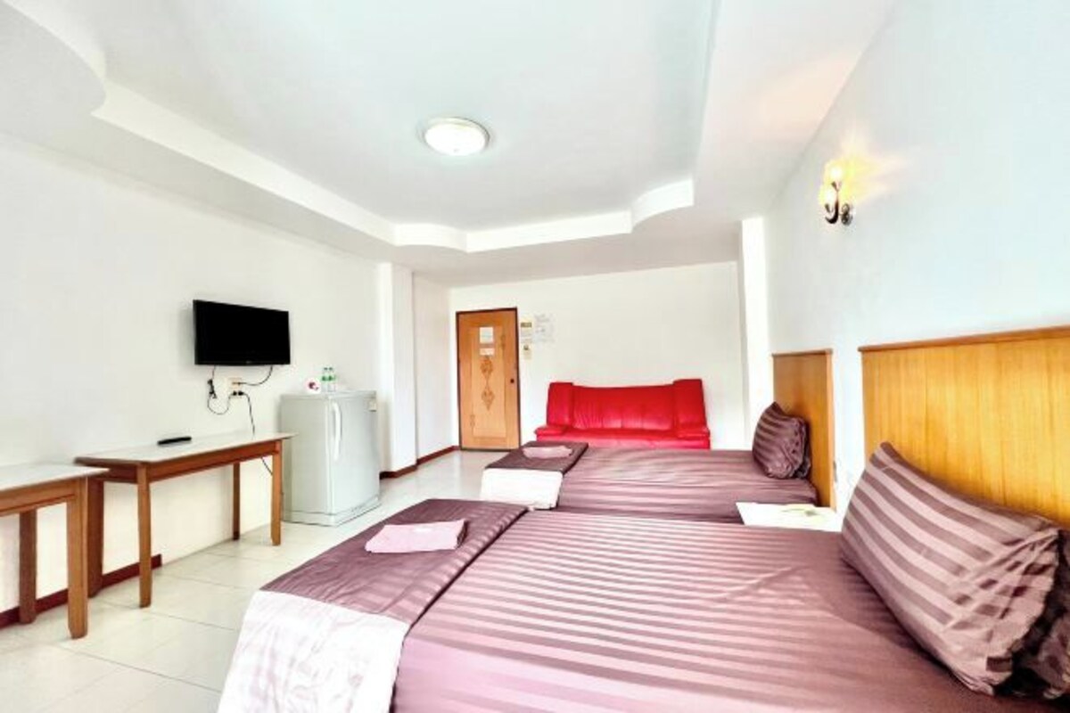 A hotel room with two beds, a television, a desk, and a refrigerator.