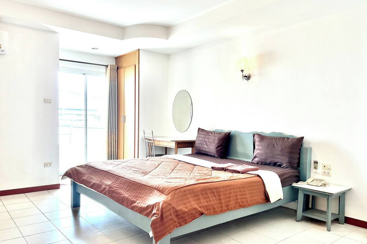 A modern bedroom with a bed, bedside table, and a mirror.