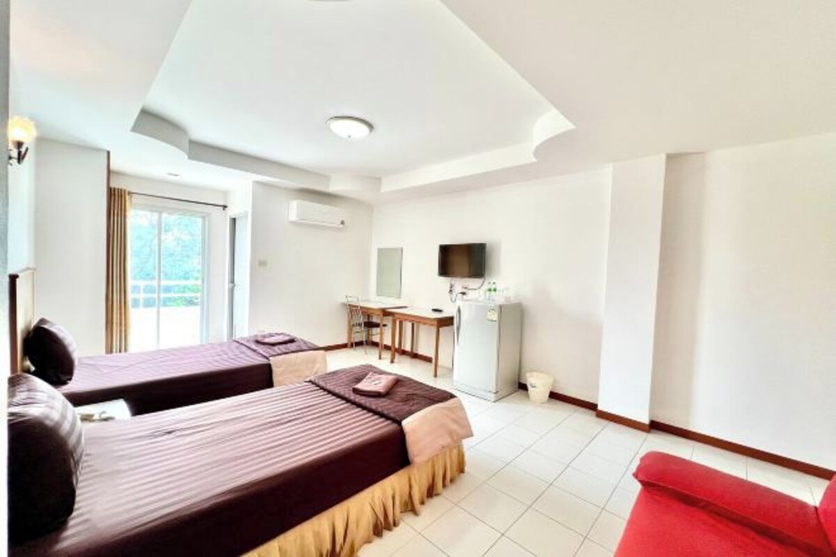 Una habitación de hotel con dos camas, un escritorio, un televisor y una silla roja.