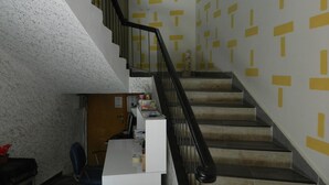 A staircase with a geometric pattern on the walls, a desk with a computer, and a chair in a room with a textured ceiling. - Sunrise Hotel (Antalya)