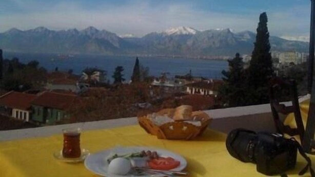 A table with a meal, a camera, and a view of mountains and a lake. - Sunrise Hotel (Antalya)