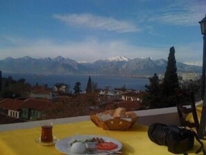 A table with a meal, a camera, and a view of mountains and a lake. - Sunrise Hotel (Antalya)