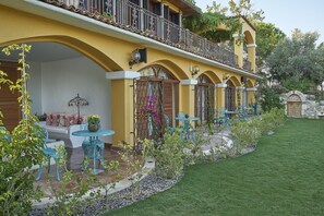 Um edifício amarelo com varanda, área de estar externa e um jardim bem cuidado.