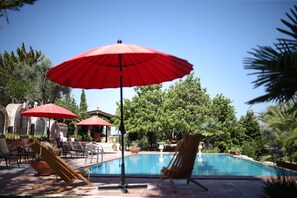A pool area with red umbrellas, lounge chairs, and a clear blue sky. - Villa Taraca Alacati Romantik Hotel (Cesme)