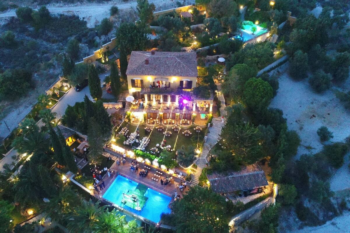 Luchtbeeld van een resort met een groot zwembad, een terras voor buiten eten en meerdere gastenkamers.