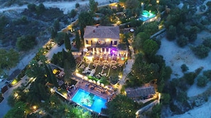 Vista aérea de um resort com uma piscina grande, área de refeições ao ar livre e várias acomodações.