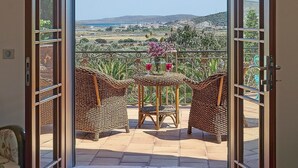 An open door leading to a balcony with wicker furniture and a vase of flowers. - Villa Taraca Alacati Romantik Hotel (Cesme)