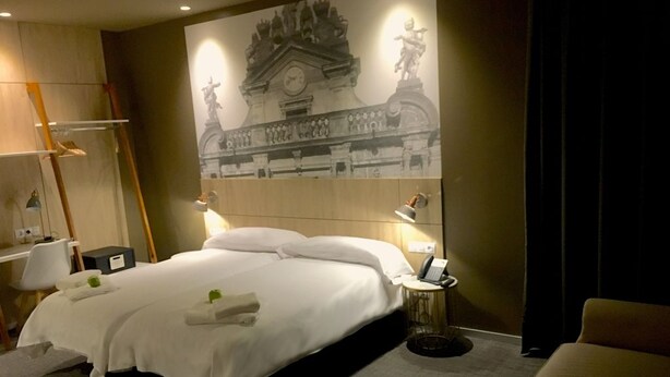 Una habitación de hotel con una cama grande, lámparas de noche, un escritorio y una silla.
