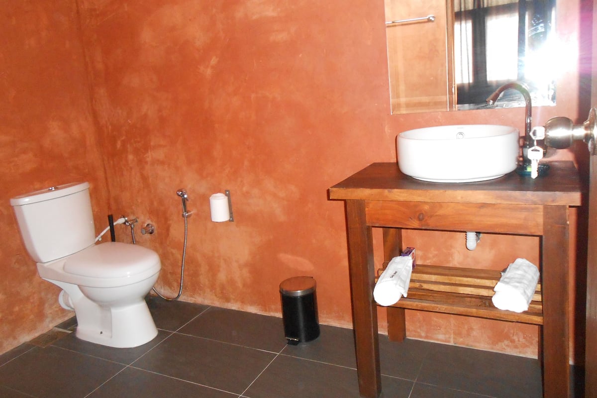 Een badkamer met toilet, wastafel en spiegel.