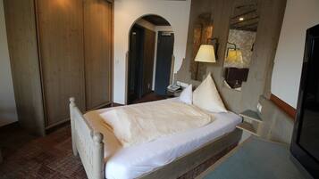 A bedroom with a wooden bed, a nightstand, a lamp, and a television.