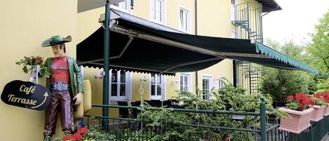 A building with a yellow facade, a balcony, and a sign reading "Café Terrasse".