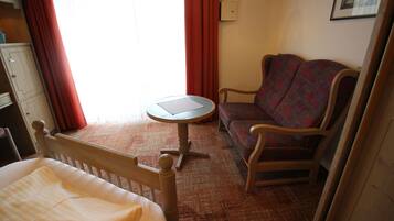 Ein Hotelzimmer mit einem Bett, einem kleinen runden Tisch, einer Couch und einem Holzschrank.