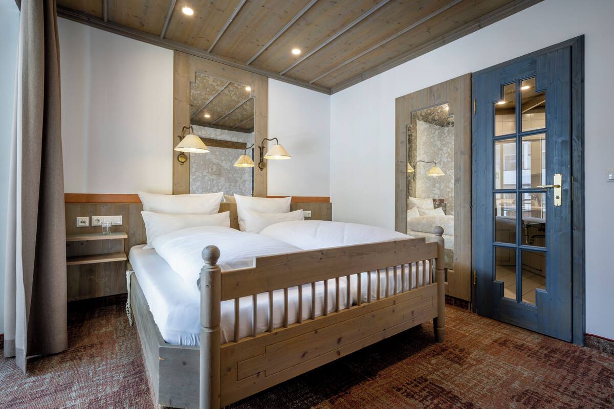 A bedroom with a wooden bed, a nightstand, a mirror, and a door to a bathroom.