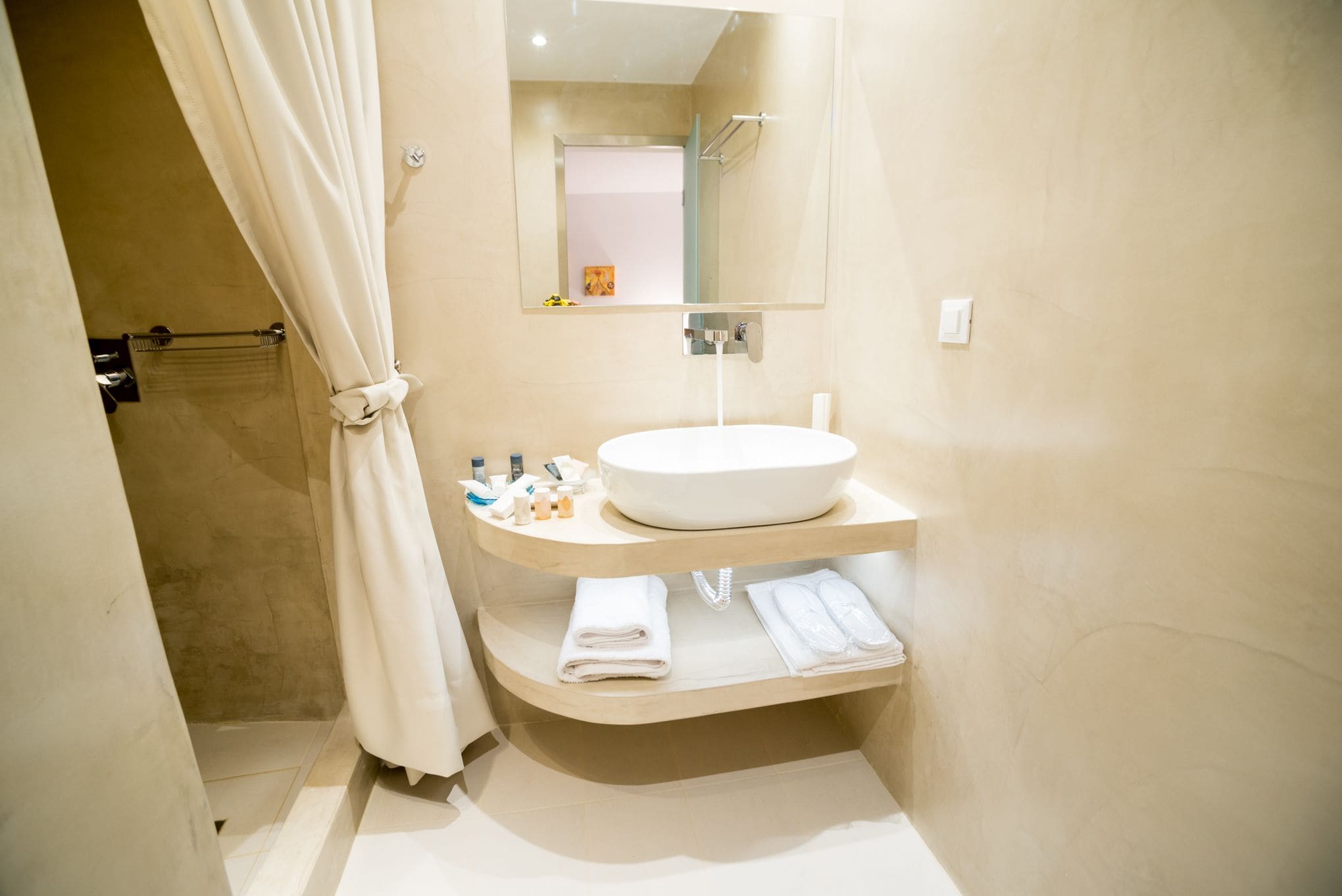 A modern bathroom with a large sink, a mirror, and a shower area.