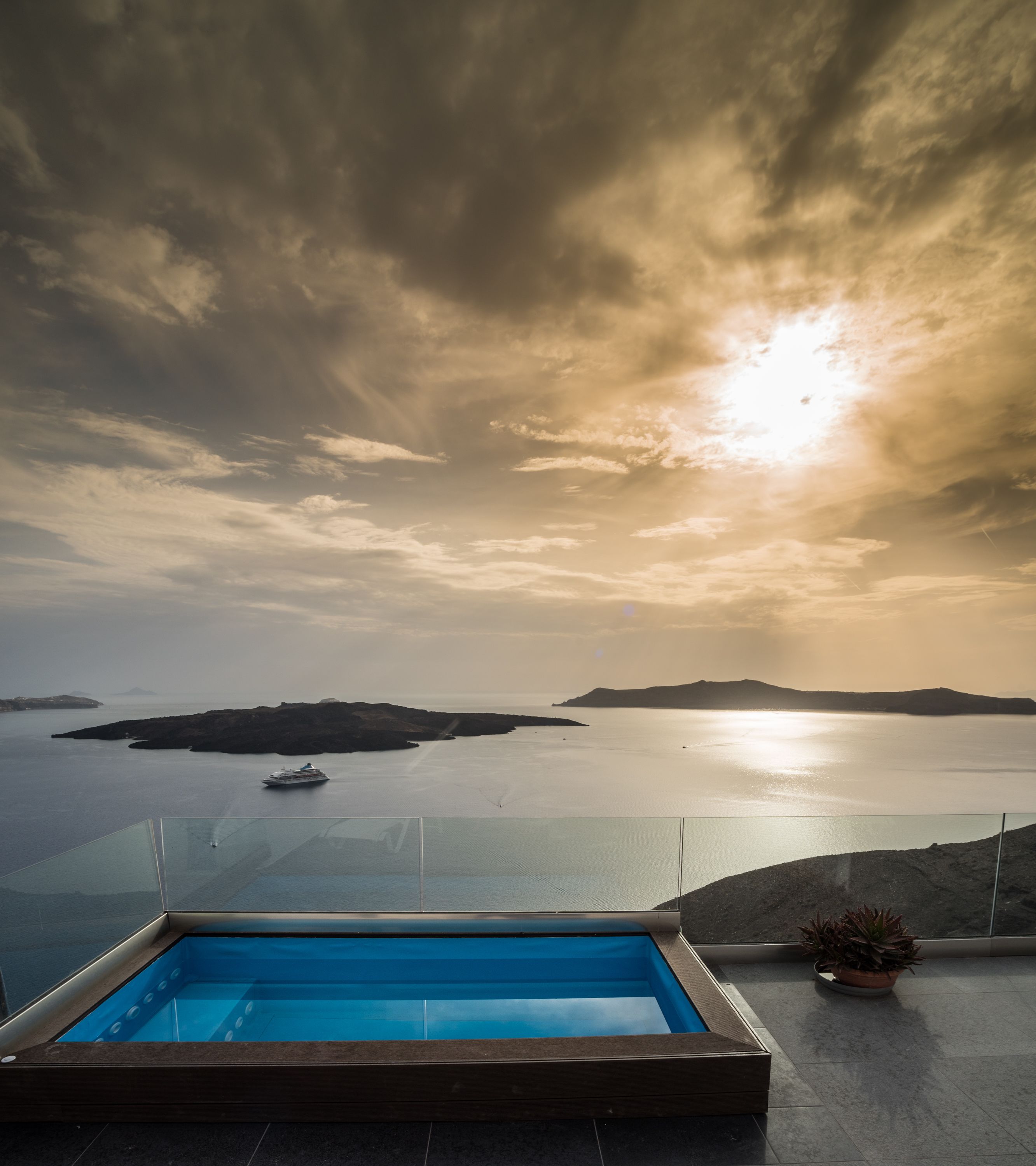 En modern infinitypool med fri utsikt över havet och avlägsna öar, särskilt vacker vid solnedgången.