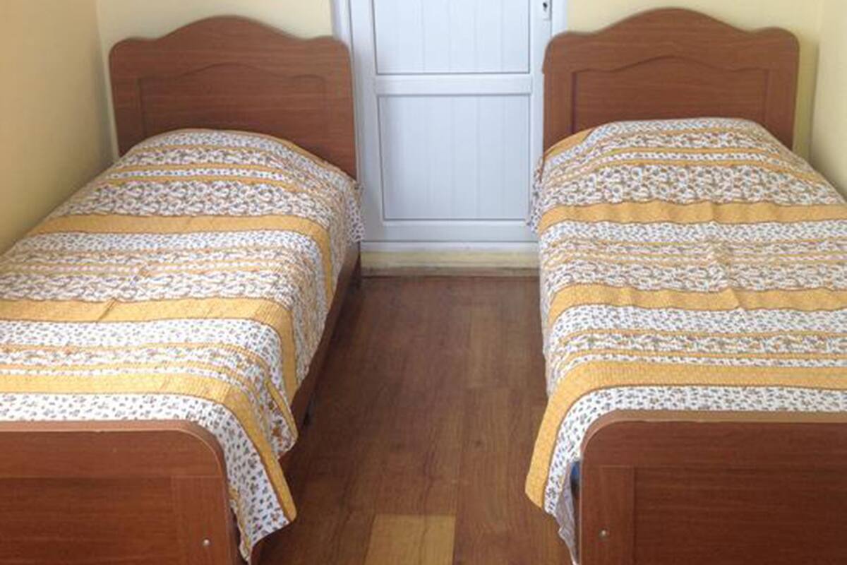 A small room with two wooden beds, a white door, and a wooden floor.