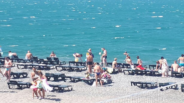 Una playa con filas de tumbonas y gente disfrutando del mar.