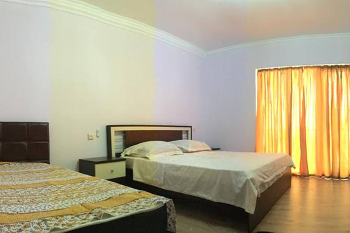 A hotel room with two beds, a wardrobe, and a television.
