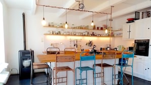 A modern kitchen with a central island, bar stools, and hanging light fixtures. - La Maison Folia (Quettreville-sur-Sienne)