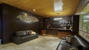 Una sala de estar moderna con un sofá de cuero oscuro, suelo de baldosas de piedra y techo de madera.