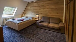 Un dormitorio con techo inclinado, cama, sofá y ventana con vistas.