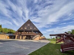 A triangular-shaped building labeled "HOTEL ZONE" with a paved entrance and a small parking area. - Hotel Žalý (Benecko)