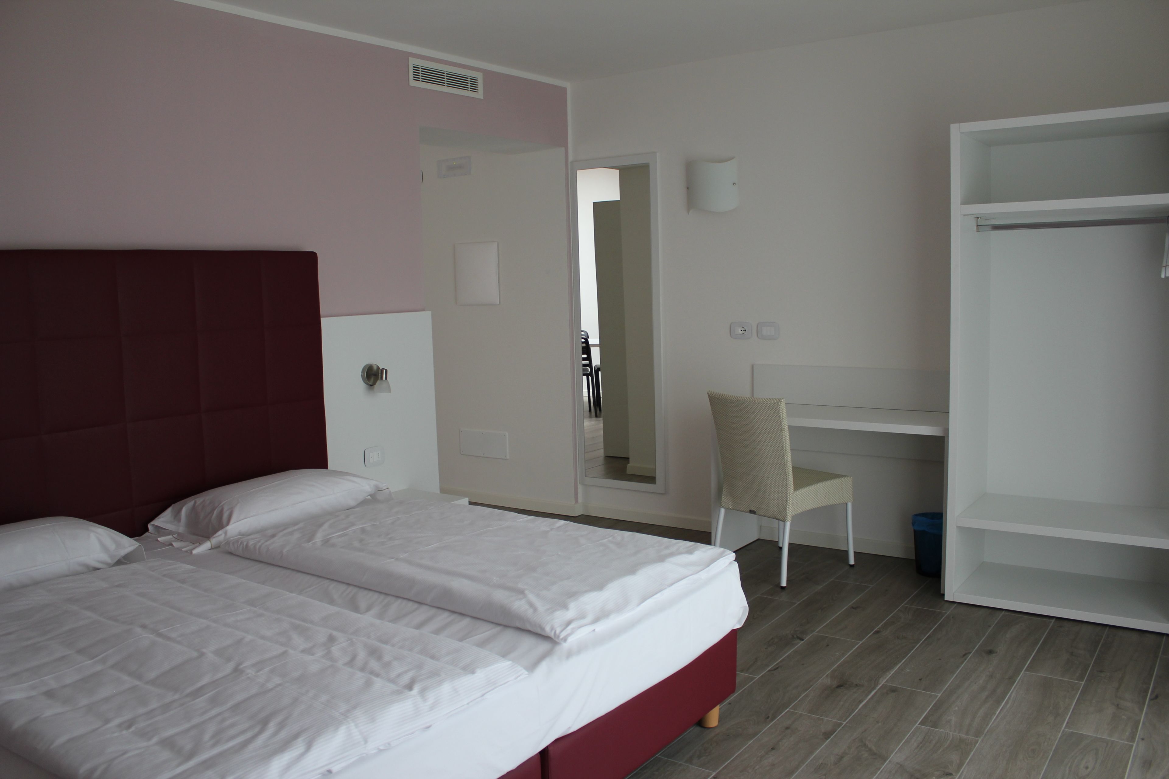 Ein Schlafzimmer mit einem Bett, einem Sessel, einem Schreibtisch und einem Kleiderschrank.