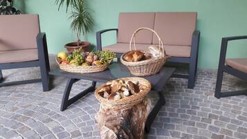 Una mesa con tres cestas de mimbre que contienen frutas, pan y setas.