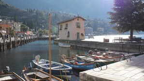 Un port de plaisance où sont amarrés plusieurs bateaux, un bâtiment doté d’un balcon et, en arrière-plan, un paysage montagneux.