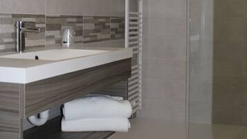 A modern bathroom with a shower, a sink, and a mirror.