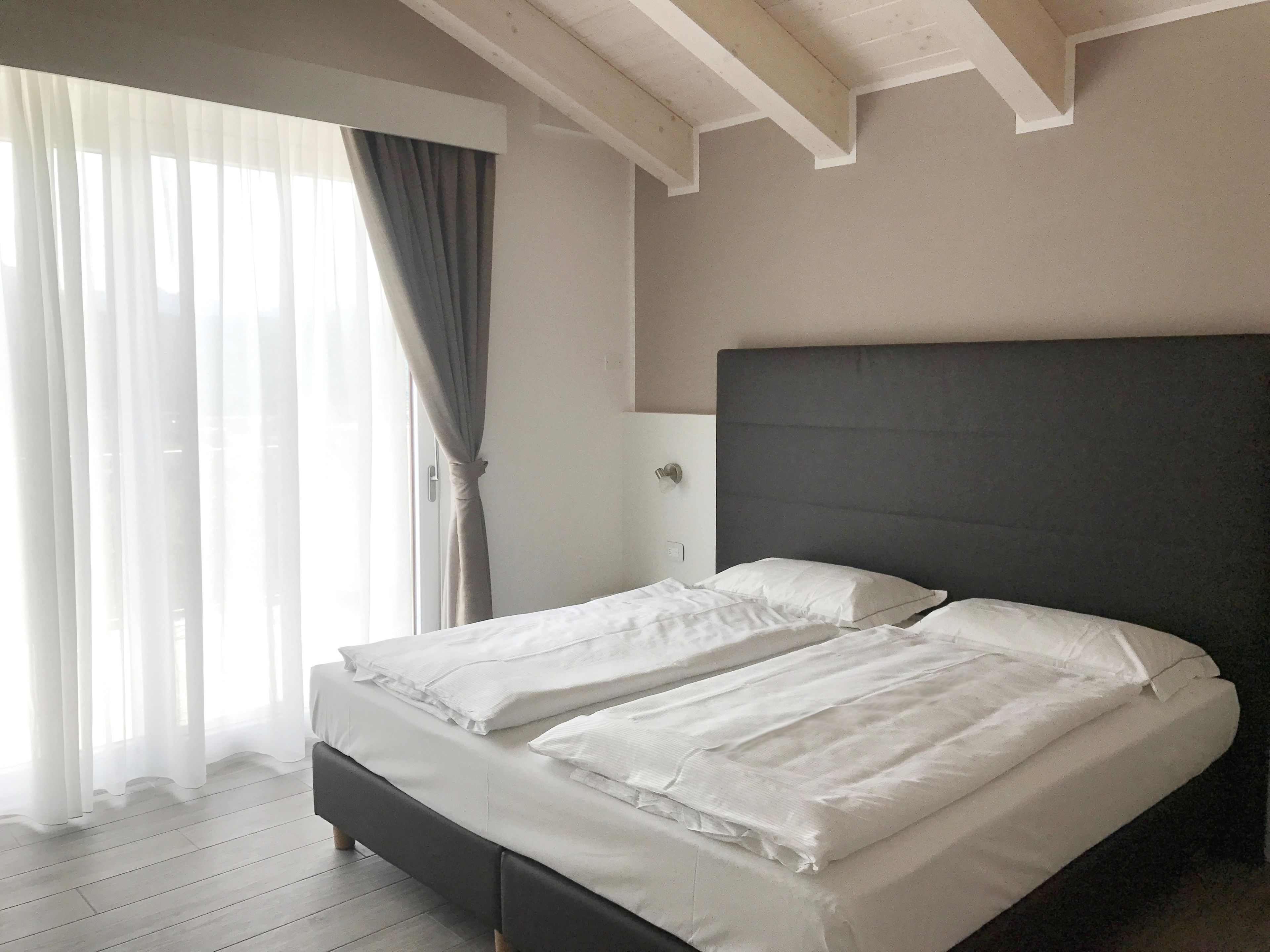 A bedroom with a bed, curtains, and a window.