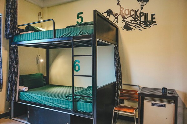 A bunk bed with numbers 5 and 6, a chair, a small table with a sign, and a wall decoration. - DMZ Hostel Hue (Hue)