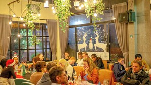 Un grupo de personas sentadas en una mesa en un restaurante con plantas colgantes y luces de cuerda.