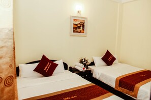 A hotel room with two beds, each with white bedding and maroon pillows. There is a framed picture on the wall above the beds, a small table with a vase of flowers, and a telephone on the nightstand. - DMZ Hostel Hue (Hue)