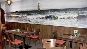 A restaurant with wooden furniture, a mural of the ocean, and a ship in the distance. - Penzion U Admirála (Kladno)