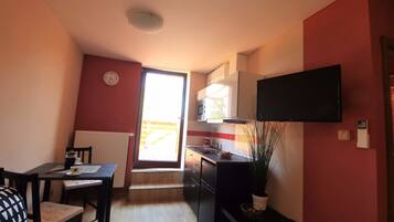 A compact kitchen with a microwave, stove, and a flat-screen TV mounted above the counter.