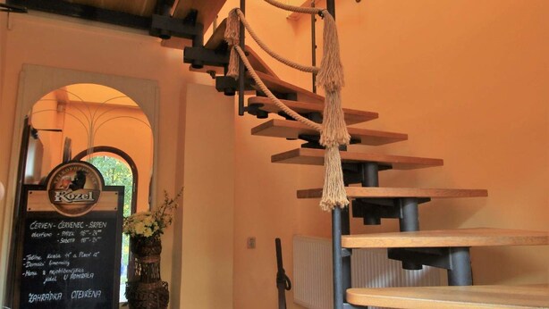 A spiral staircase with a rope ladder, a signboard with menu options, and a potted plant. - Penzion U Admirála (Kladno)