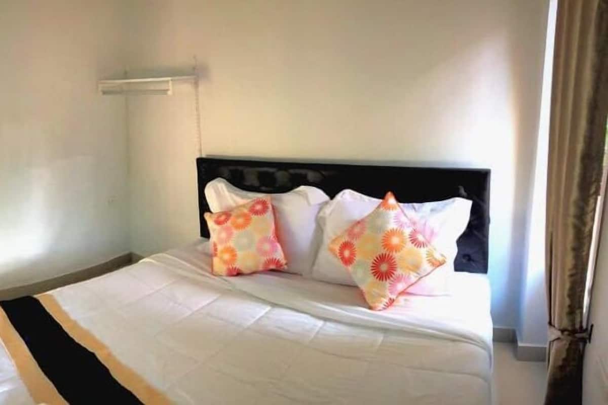 A neatly made bed with a black headboard and two decorative pillows.