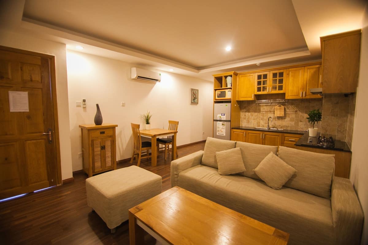 A compact living space with a kitchenette, a dining area, and a seating area with a sofa and ottoman.