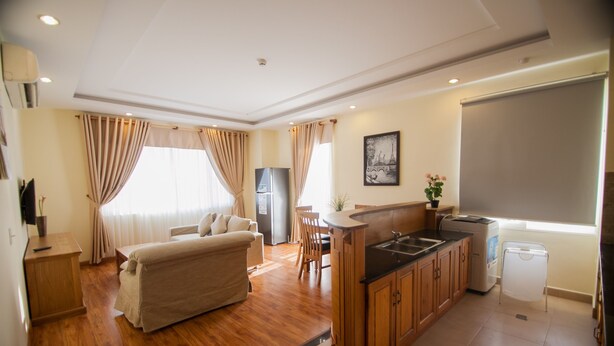 Een kleine hotelkamer met een kitchenette, een eethoek en een bed.