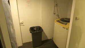 A small room with a washing machine, a trash bin, and a door with a sign. - Taipei Breeze B&B (Taipei)