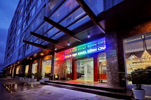 A hotel entrance with a modern facade, large glass windows, and a neon sign. - Rigel Hotel (Nha Trang)