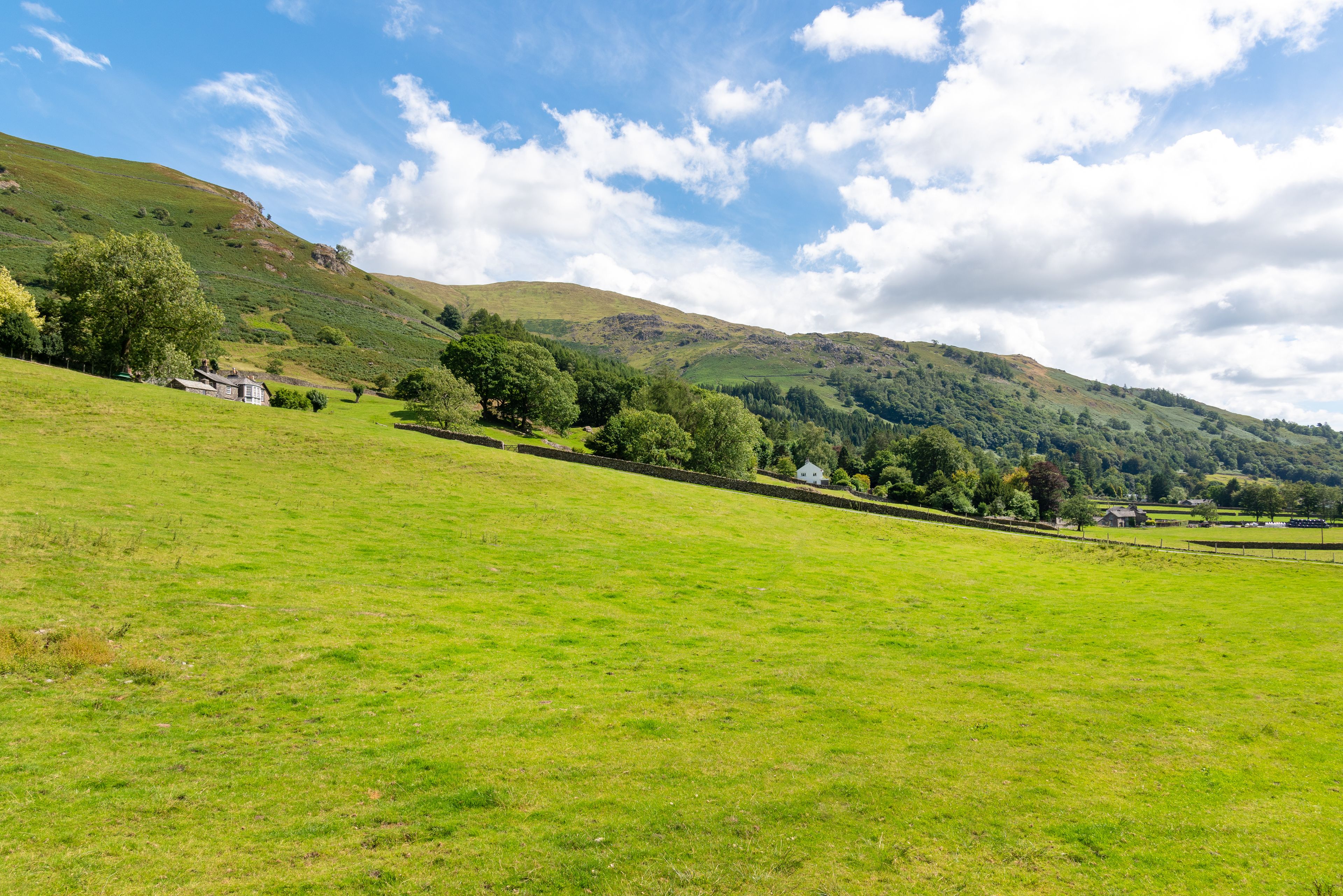 A rural landscape with rolling hills, a clear sky, and scattered houses.