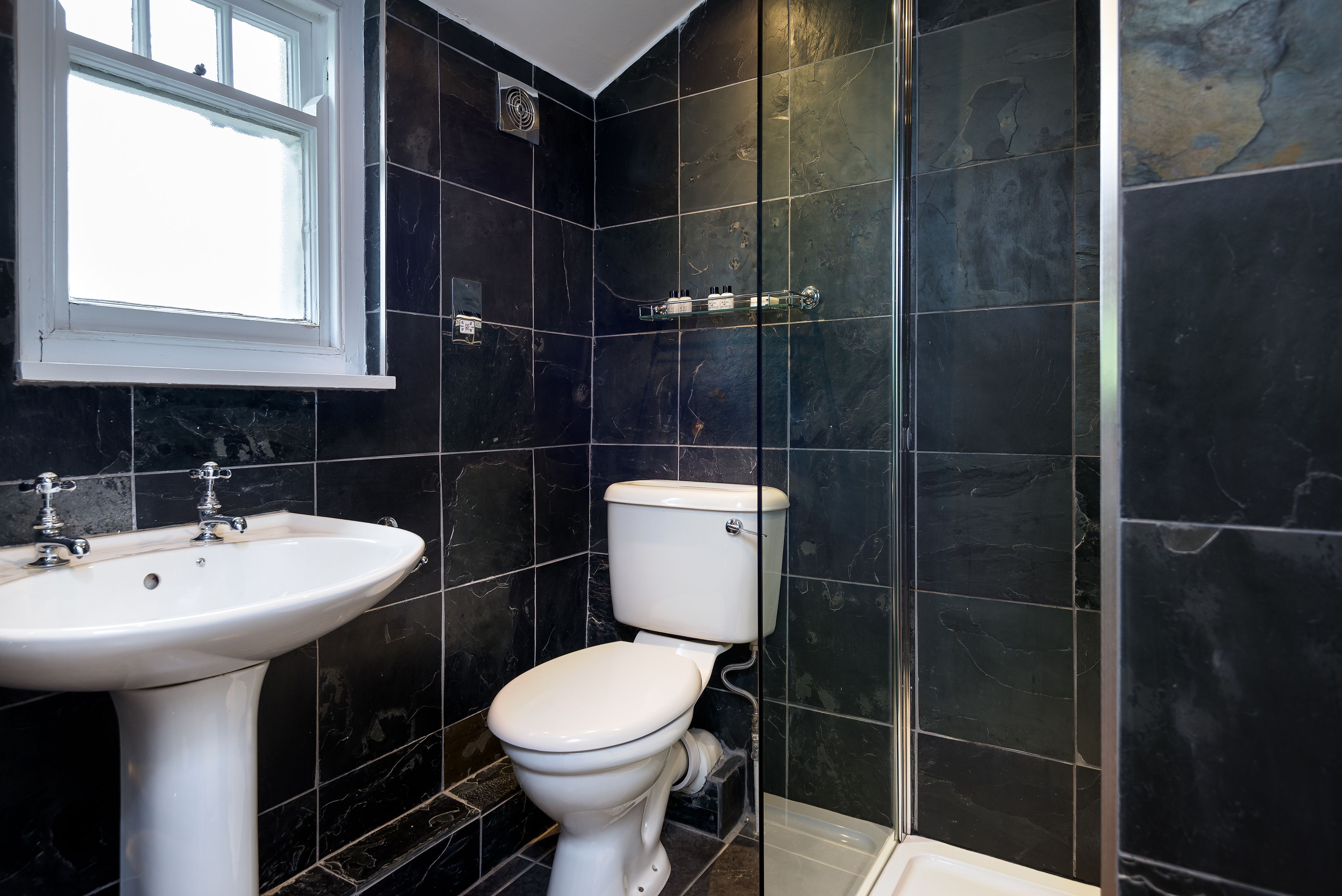 A bathroom with a white sink, toilet, and a window.