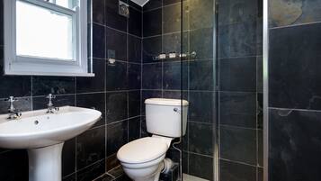 A bathroom with a white sink, toilet, and a window.