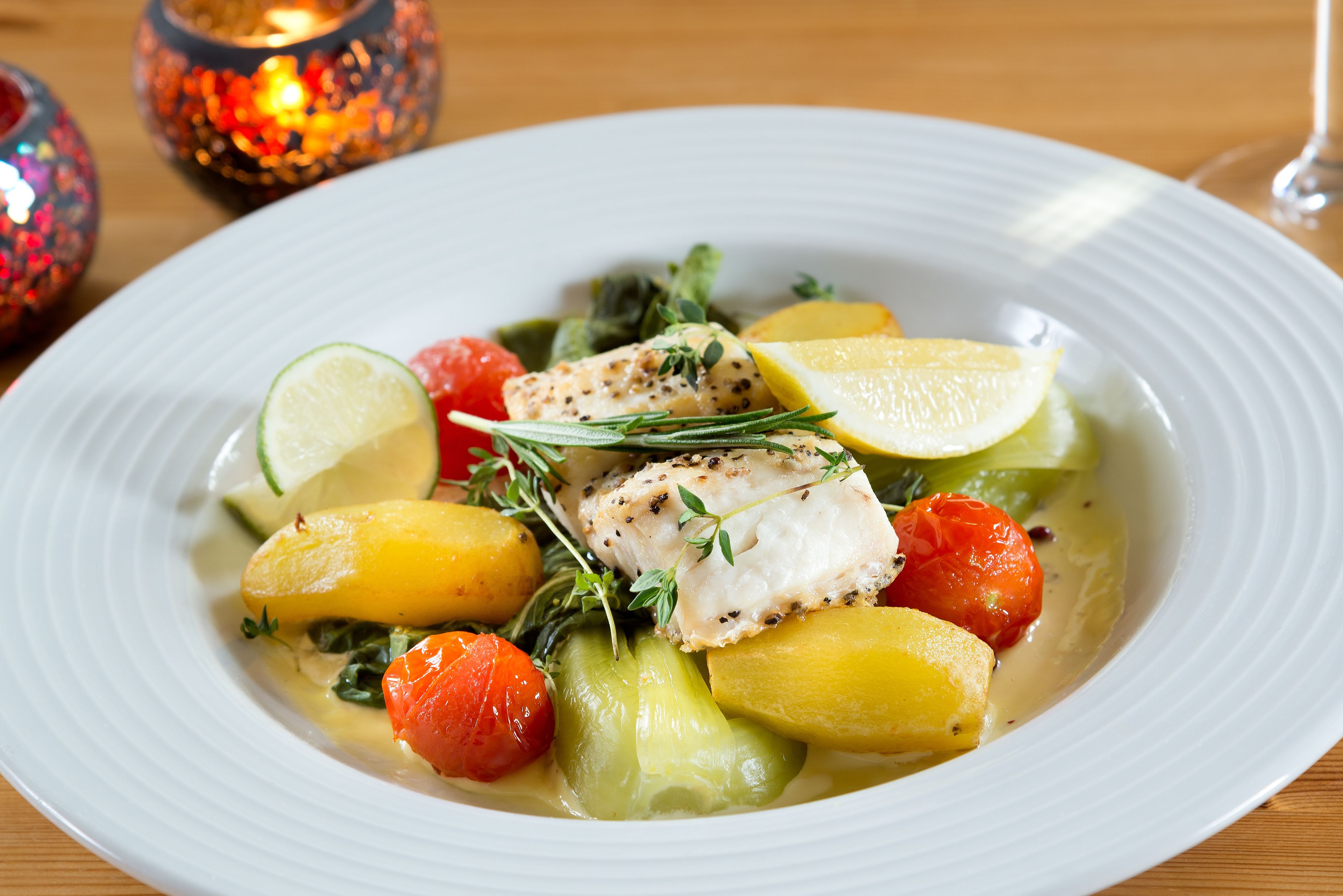Ein weißer Teller mit Fischfilet, Zitrone und Gemüse.