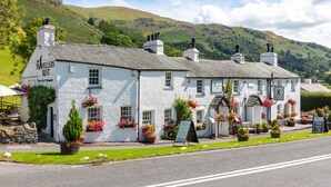 A white building with multiple chimneys, a sign reading "The Travellers Rest," and flower boxes on the windowsills. - Traveller's Rest Inn (Ambleside)