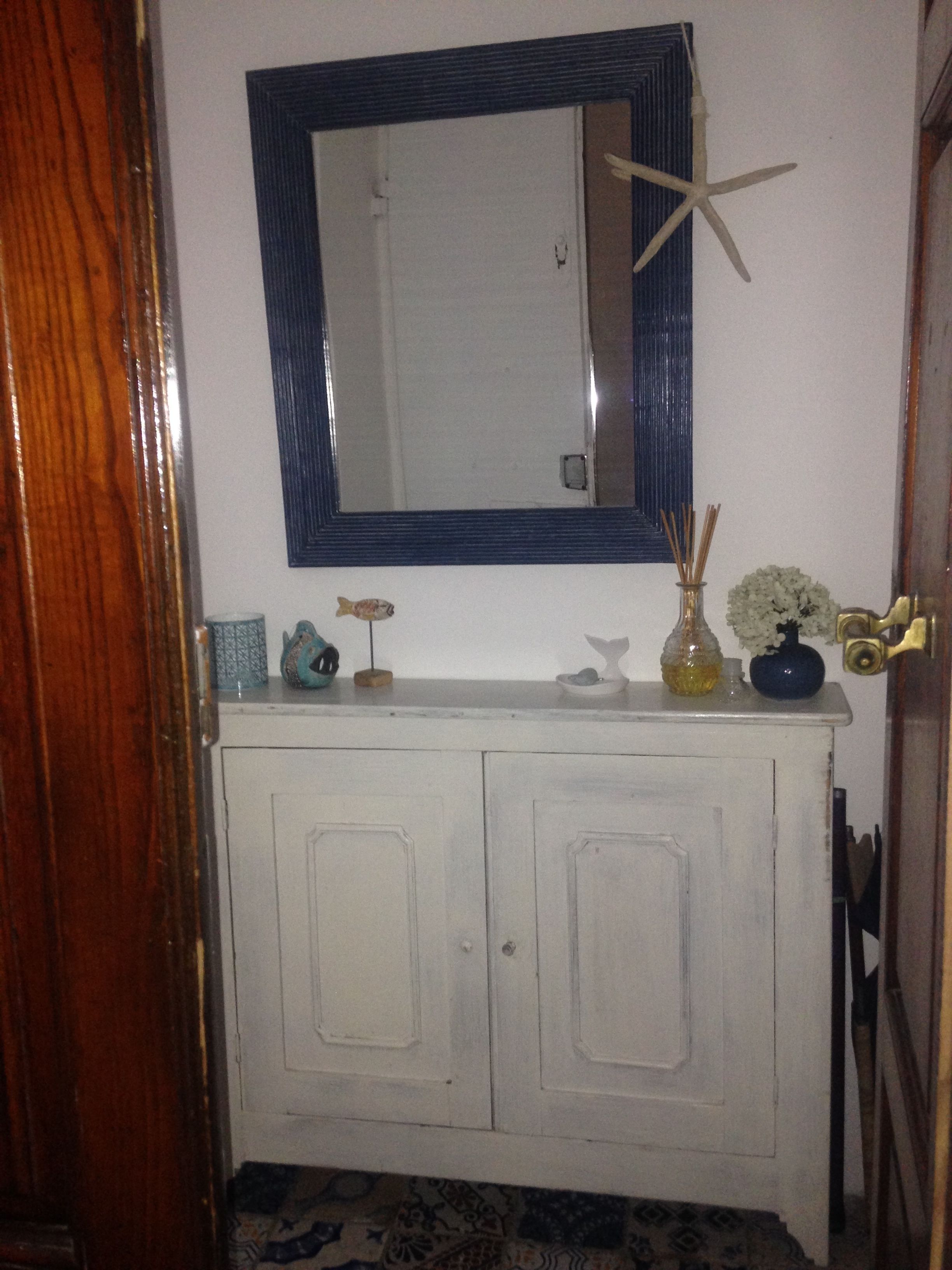 A bathroom with a white vanity, a mirror with a blue frame, and a starfish decoration.